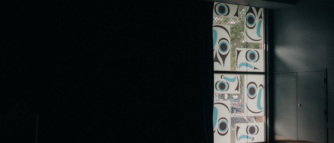 A window mural of eight salmon heads using Salish graphic elements.
