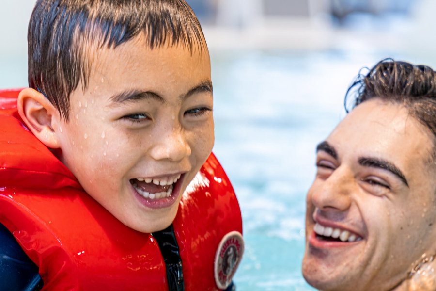 A boy and an instructor swimming. 
