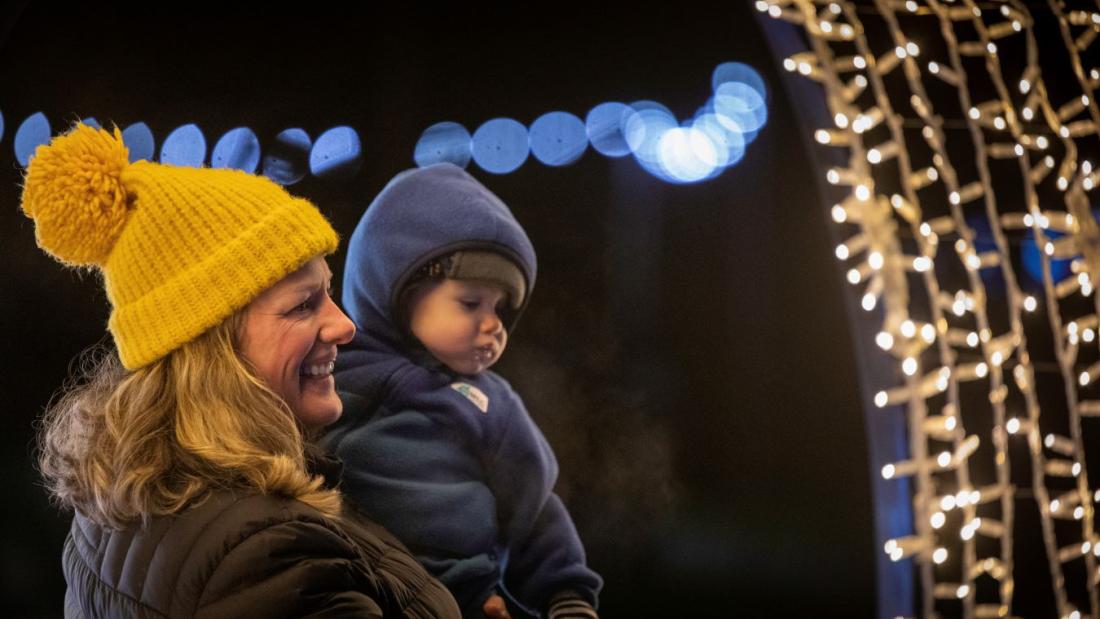 Child and adult looking at archway of lights