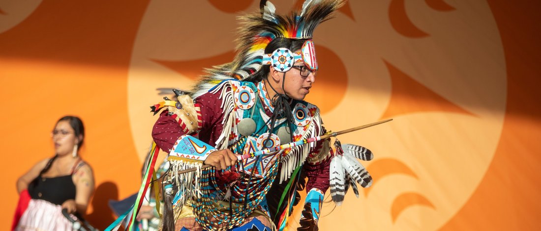 a man in a traditional indigenous outfit performing at NIPD