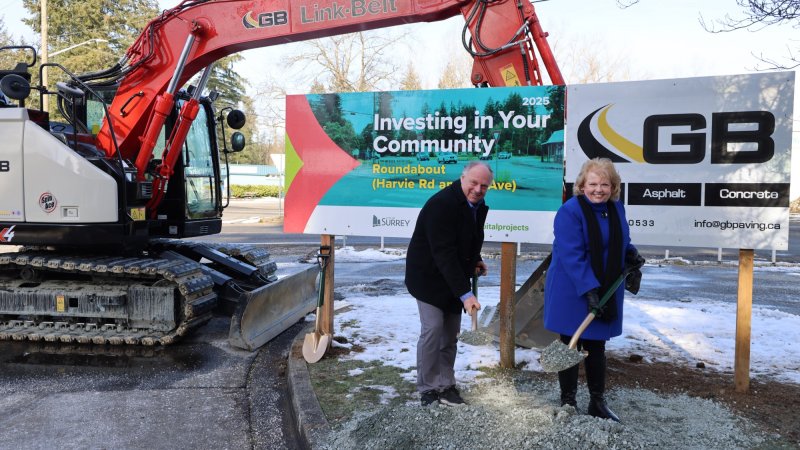 Mayor Brenda Locke at a groundbreaking ceremony for the Port Kells roundabout project, holding shovels in front of an excavator and project sign.
