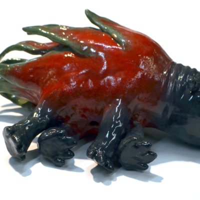 A ceramic of a dark green hippopotamus morphing into a dragonfruit.