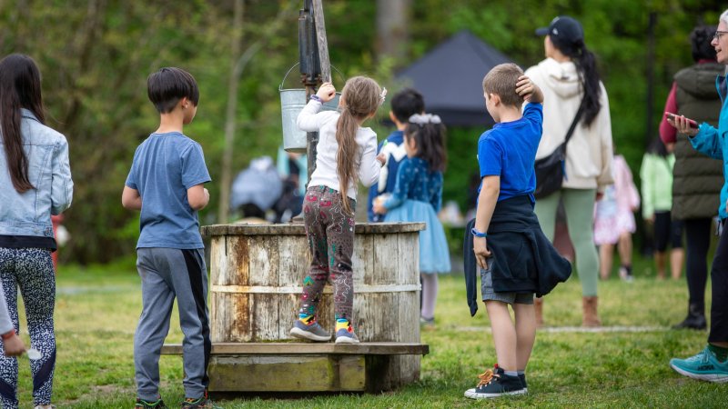 Kids gathered around the water pump at Spring Fest